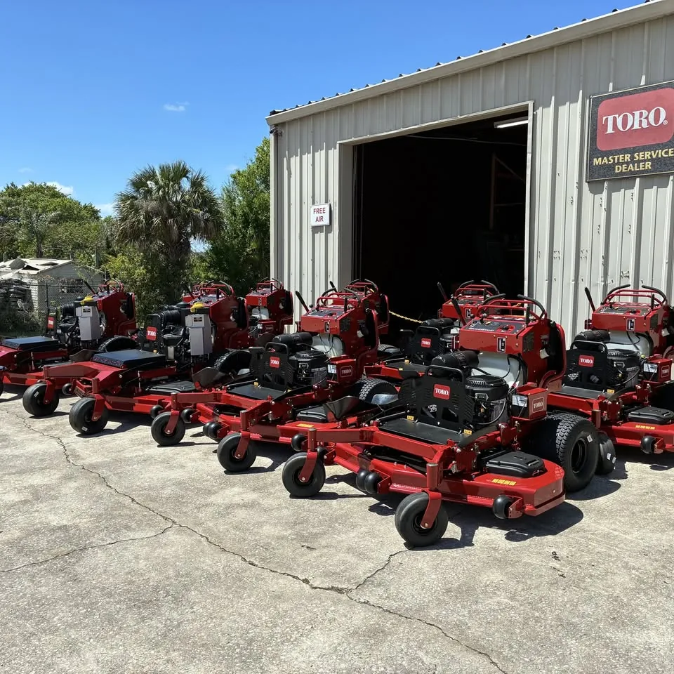 A row of red Toro mowers outside the shop